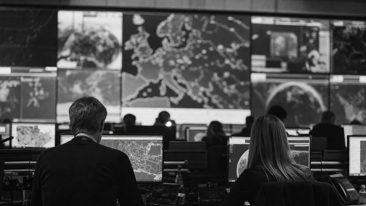 European crisis-management operations centre, a wall of map screens and staff at workstations seen from behind (AI-generated image)