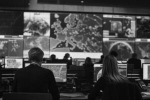 European crisis-management operations centre, a wall of map screens and staff at workstations seen from behind (AI-generated image)