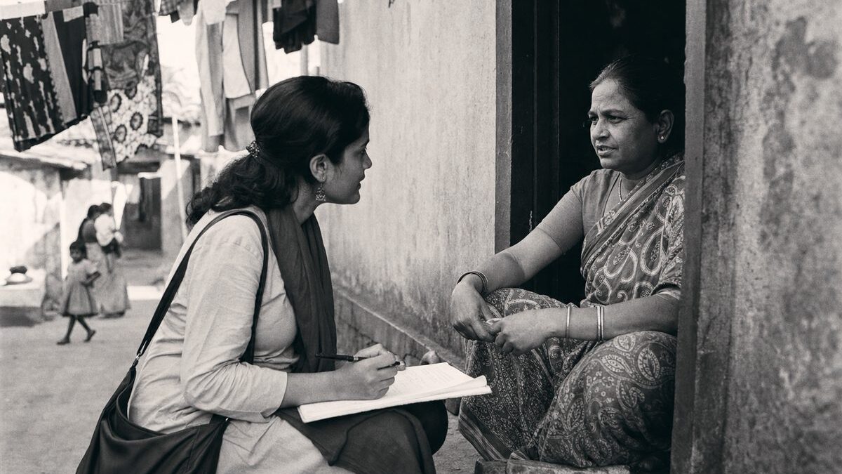 Researcher with a questionnaire sitting on a doorstep interviewing a resident, laundry lines overhead (AI-generated image)