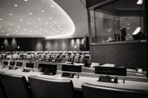 Large multilateral conference chamber before a session, curved desks with country nameplates and microphones (AI-generated image)