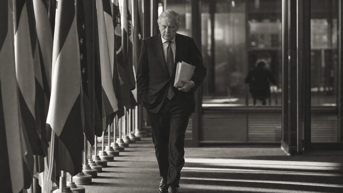 European institutional corridor lined with national flags, an official walking with briefing papers (AI-generated image)