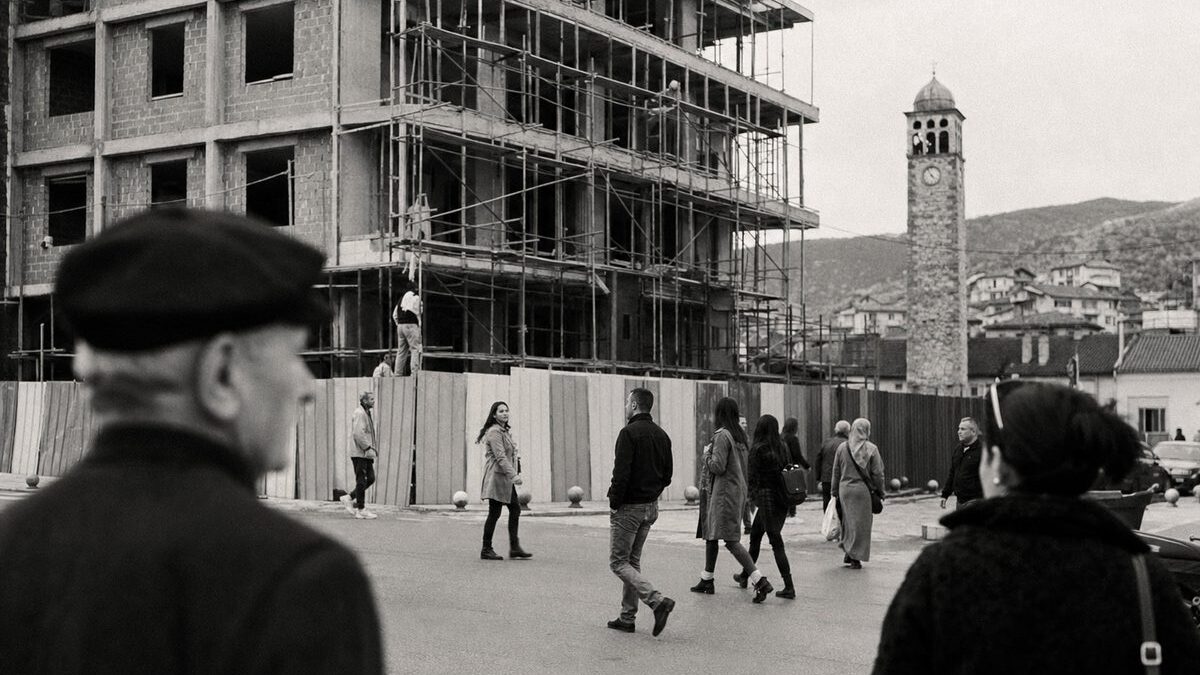 Town square in Kosovo with a half-built administration building under scaffolding and an Ottoman clock tower (AI-generated image)