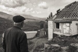 Hillside village in Georgia, a house roof under repair, an elderly man looking across the valley (AI-generated image)