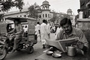 Busy Lahore street with rickshaws and pedestrians in front of a government building (AI-generated image)